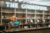 A woman wearing a uniform standing in front of a bar. There is a sign that reads "The Goosepool" above her head.
