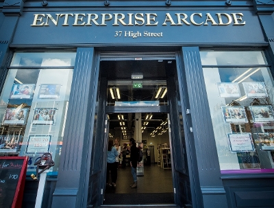 The entrance to Enterprise Arcade with people inside and posters in the windows